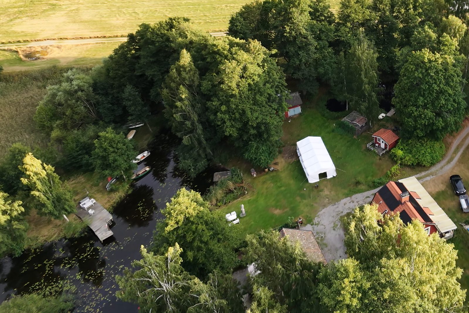 Gården i Skedevi ovanifrån med tält, brygga och gärden.