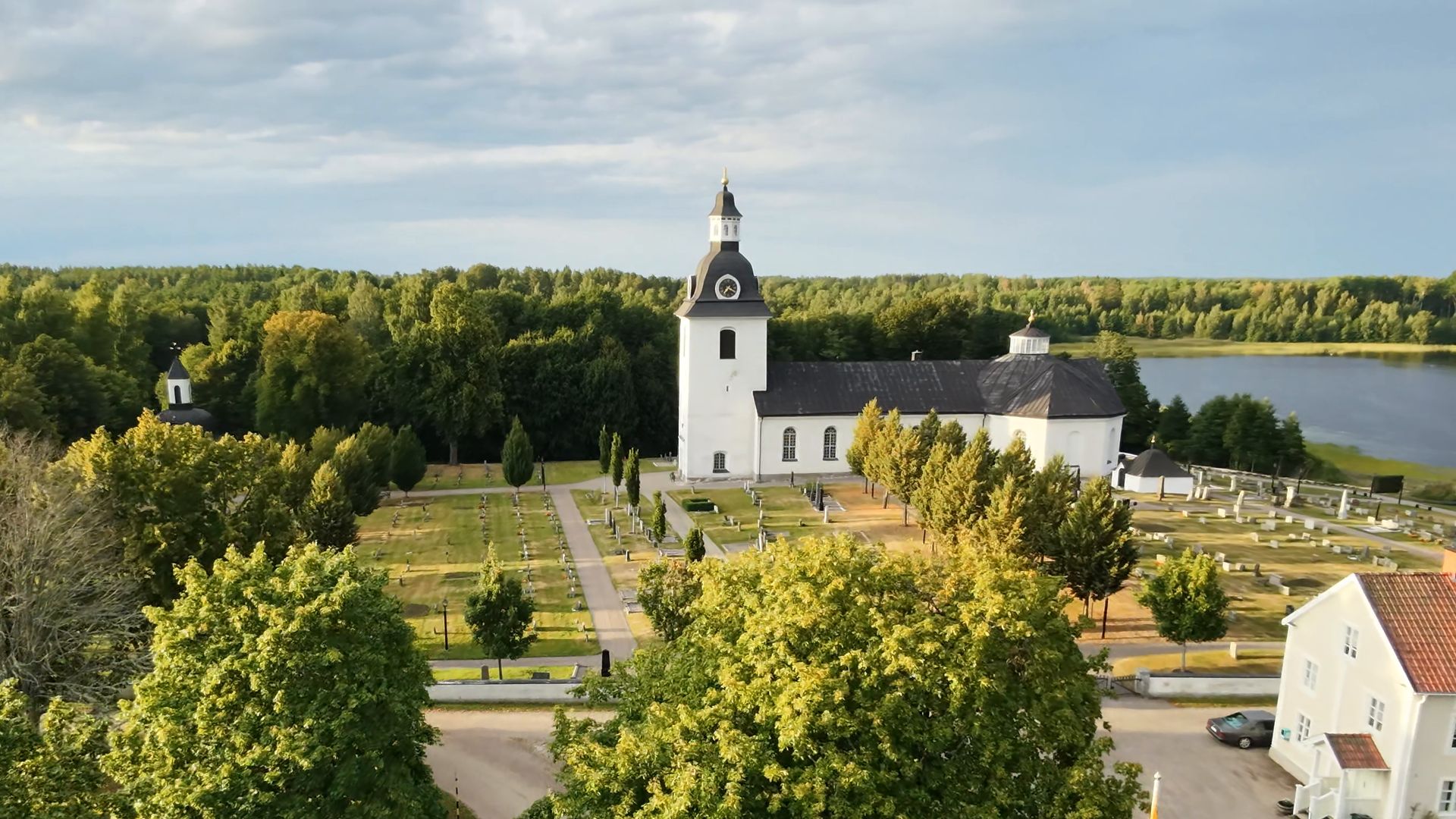 Skedevi kyrka från luften med sjön bakom.