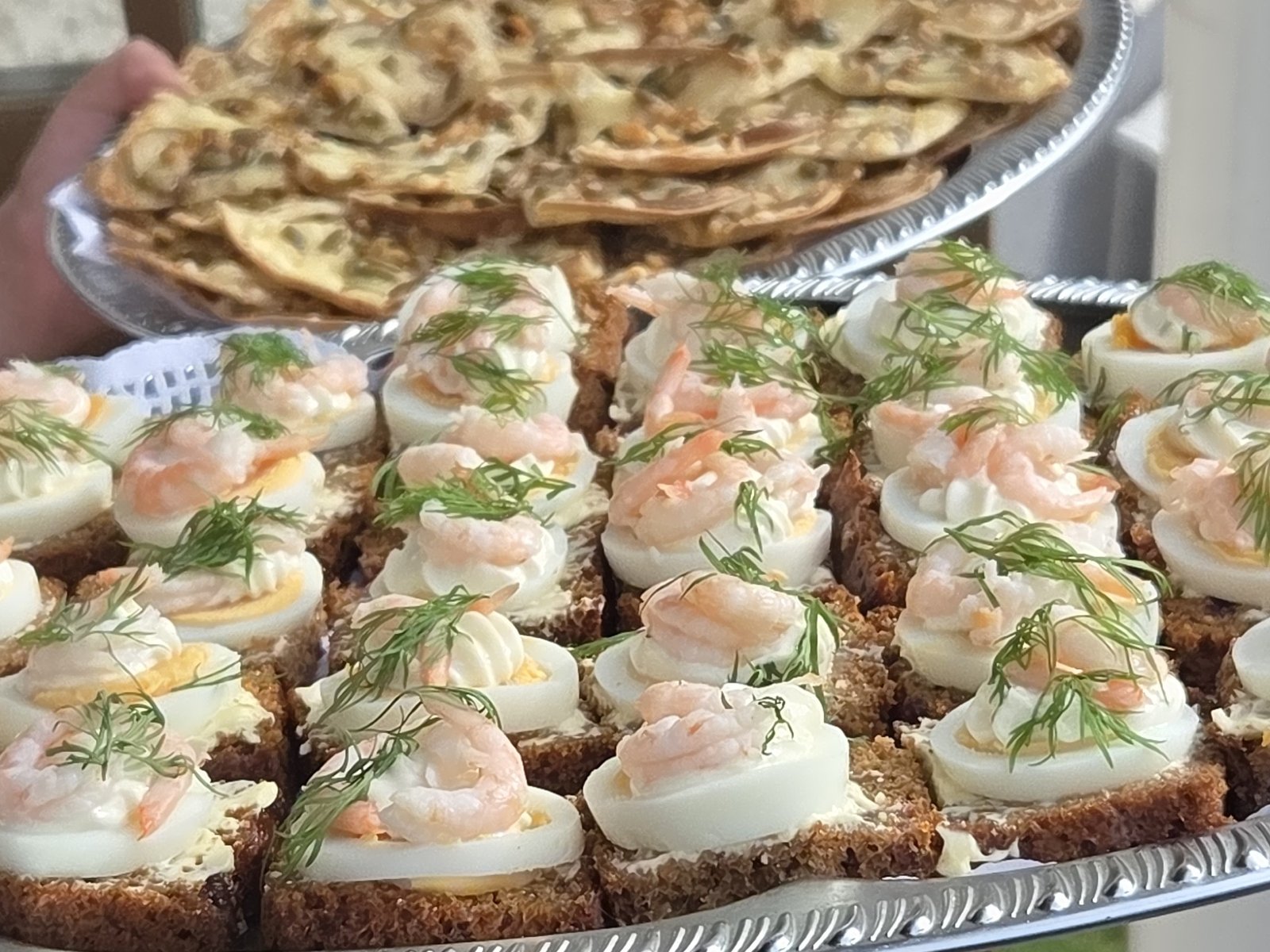 Räk- och äggsmörgåsar på silverfat, framburna utomhus.